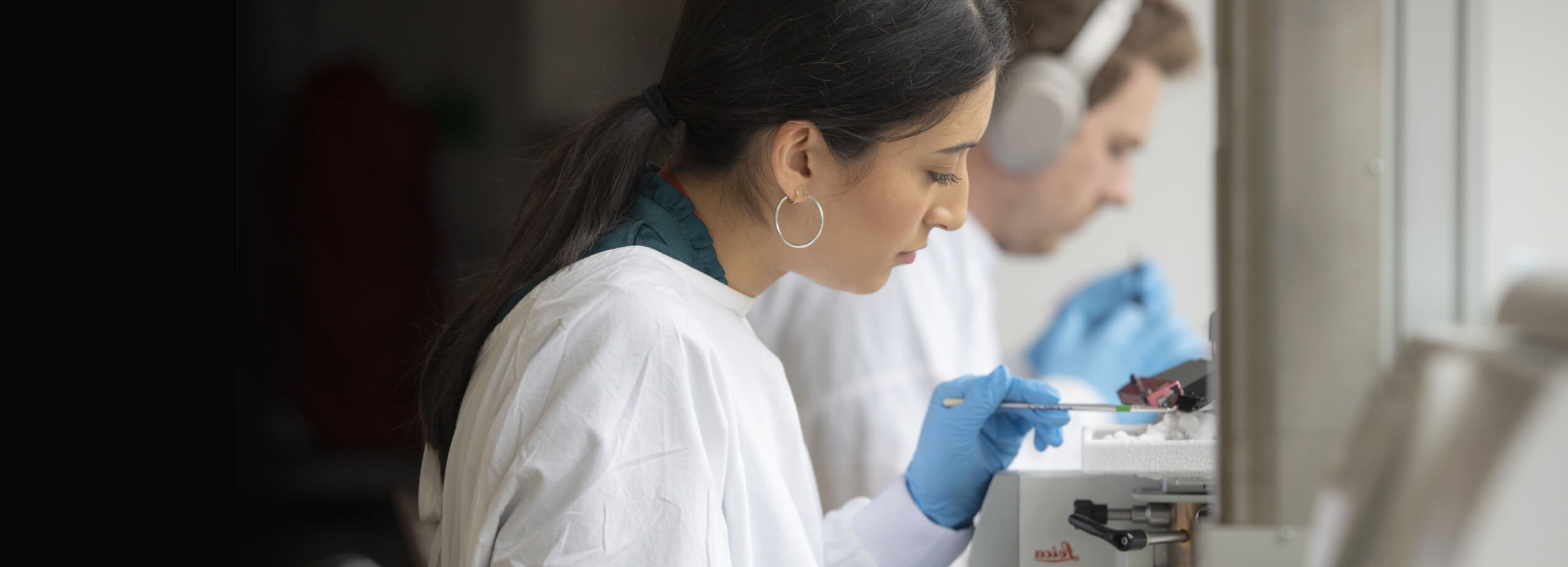 Image shows a female scientist with a white lab coat working in a lab